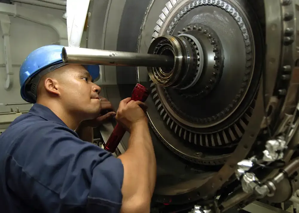 US Navy Aviation Machinist inspects a high pressure turbine of an F18 jet engine to verify that the carbon seal is intact aboard nuclear powered aircraft carrier USS Enterprise