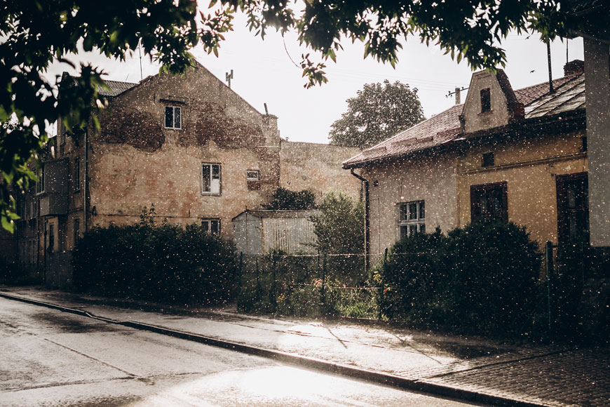 A beautiful old cobblestone street in a light rain shows an antique open-topped channel drain