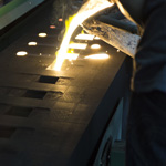 A crucible pours molten metal into a line of sand casting molds