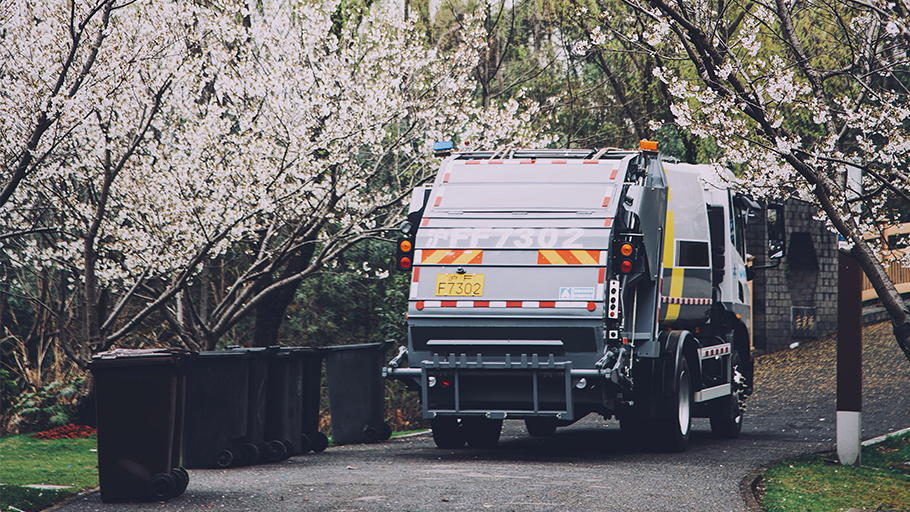 Empty garbage bins and a garbage truck in a clean park