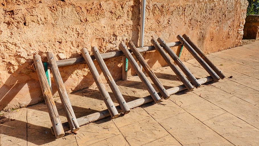 An old wooden ladder style bike rack mounted against a wall