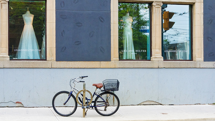 An original ring-and-post bike rack with a bike locked to it outside of a store front