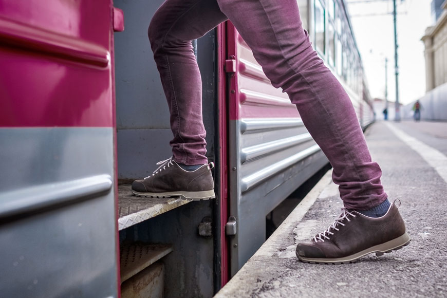 A close shot of a man’s lower legs clad in purple jeans climbing on to a commuter train.