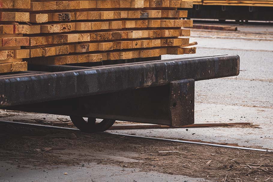 A kiln-cart laden with lumber sits on a rail surrounded by sawdust and wood debris