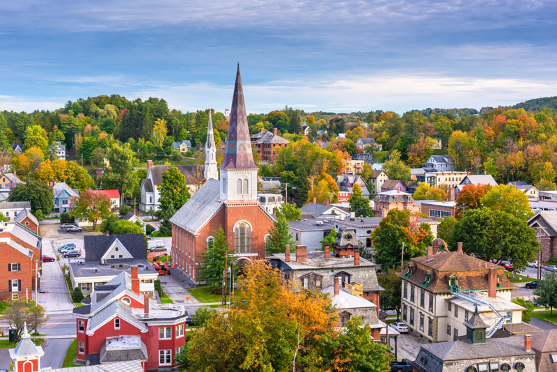 A town in Vermont in autumn populated with red, orange, and yellow trees