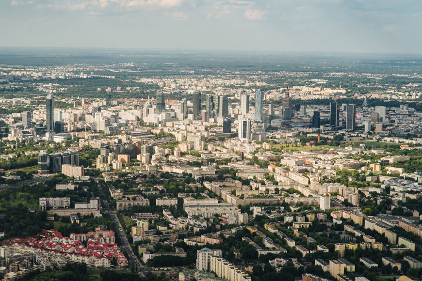 Drone image of urban tree canopy in sprawling city: line of trees between buildings and clusters in parks