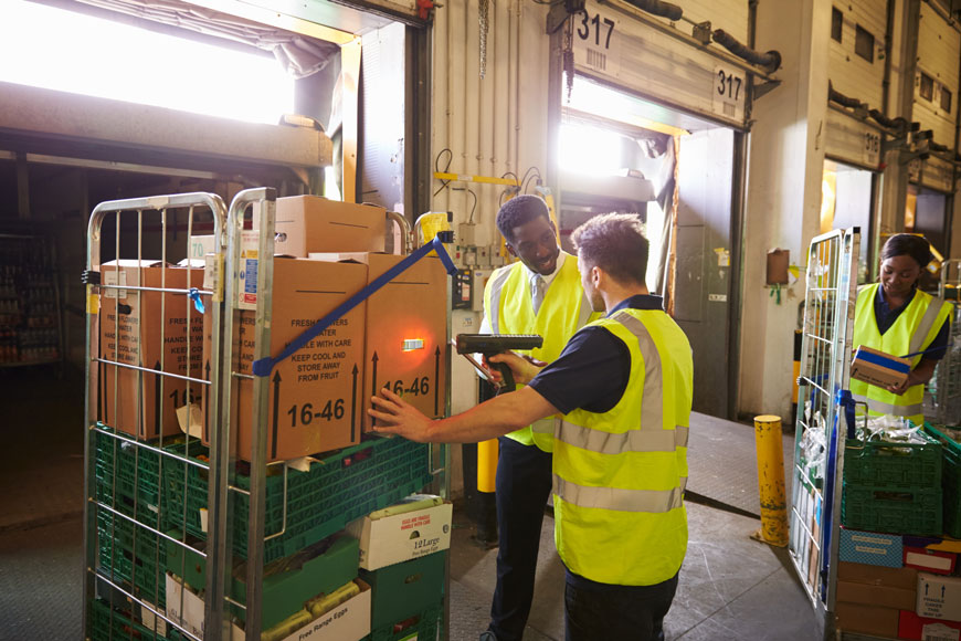 Workers fill a truck in a loading bay protected by warehouse bollards