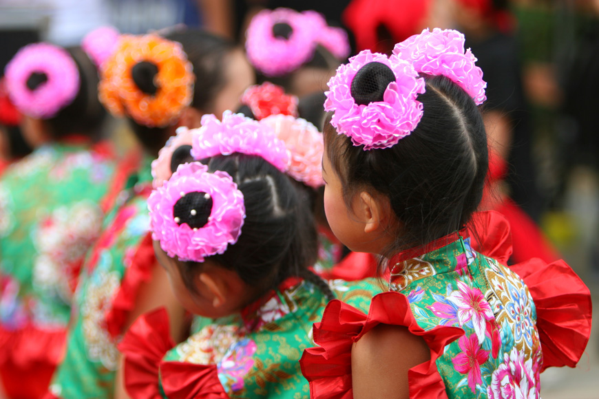 Dressed-up children with ruffled pink ties in their hair wait to perform a Lunar New Year dance.