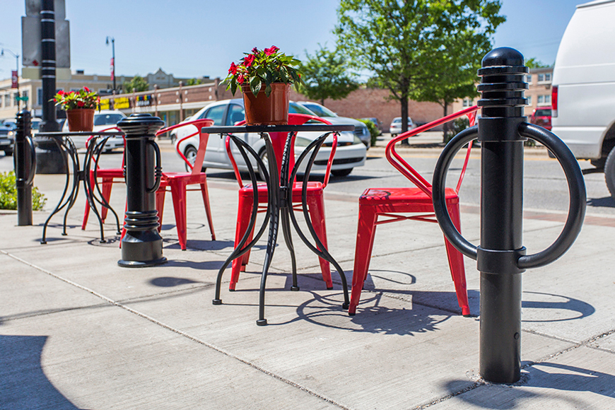 Decorative bicycle bollards enhance a patio with red chairs and tables in front of a café