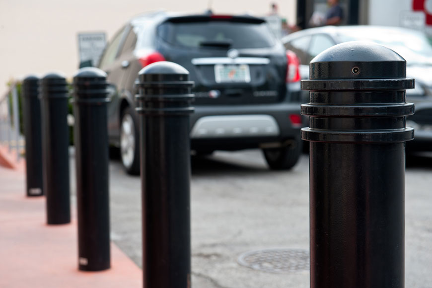 Ring-topped black bollards in the foreground, blurred cars in background