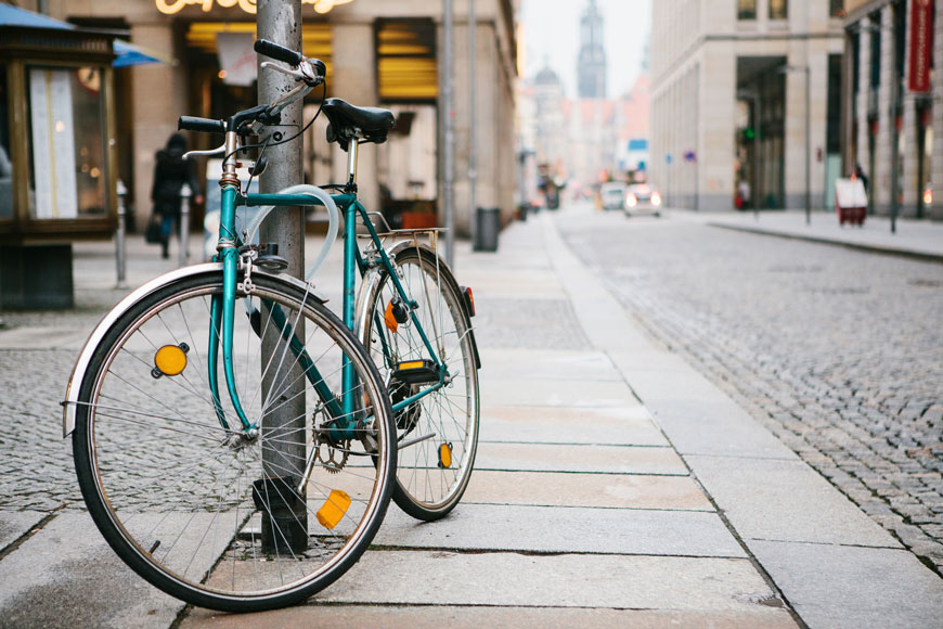 Bicicleta bloqueada al poste de metal con un cable de bloqueo en una calle europea