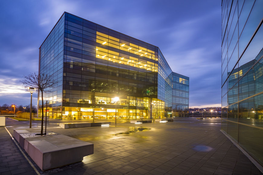 An office tower is lit from within in the purple of twilight