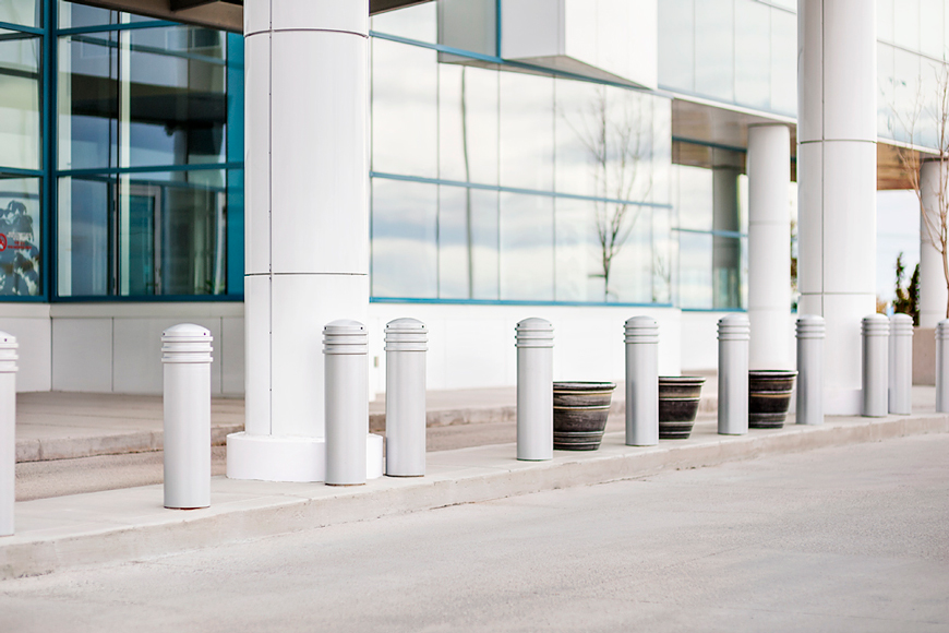 White bollards blend in with a white and glass building